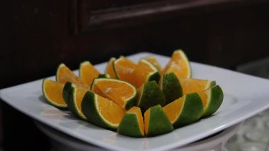 portakal dilimleri yeşil Vietnam portakalları turunçgiller bir dalda asılı, parlak yapraklarla çevrili. Açık havada doğal ışık altında, canlı ve taze detayları vurguluyor.