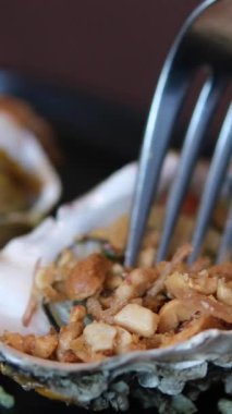 Kabuklu taze midye dolması. Bir çatalla kabuğundan yemek çıkarmak. Fırında istiridye.