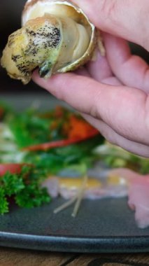 Bullot Salyangozu yemek çubukları sahnesiyle salyangozu çıkarır ve tahta kürdan kullanarak istiridye etini kabuğundan çıkarır. Yüksek kalite 4k görüntü