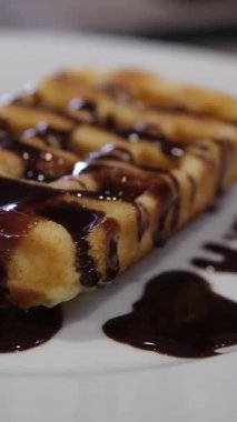 Vejetaryen çikolata soslu lezzetli waffleların statik çekimi siyah arka planda aşağı akıyor.