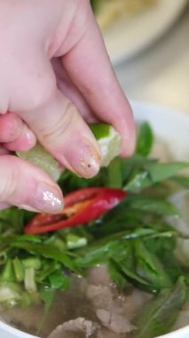 Limonlu çorbaya sıkışan el, Bangkok 'un hareketli restoranlarında bir kase Po' nun üzerine limon sıkıyor ve bulaşık tadını arttırıyor. Yüksek kalite 4k görüntü
