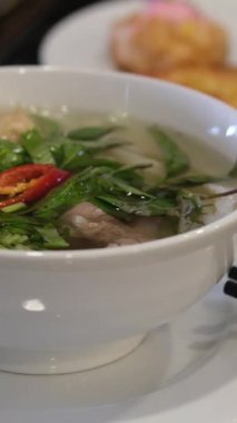 Beyaz tabakta fesleğen ve kırmızı biberli Vietnamlı pho bo bo