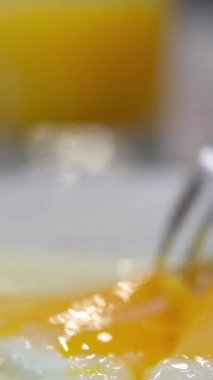 Omleti kesen çatal ve bıçağın yakın çekimi ve tabakta güneşli yumurtalar. portakal suyu, mango suyu öğle yemeği.