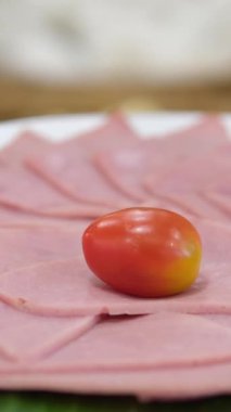 Tabakta jambon. Hafif arka planda vişneli domatesli et lezzeti. Maydanozlu hindi jambonu. Beyaz masa örtüsünde soğuk aperatif. yakın plan tedavi.