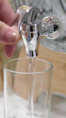 Saf su, açık gri arka planda cama yakın çekim olarak döküldü. Süper yavaş çekim. Susuzluğu giderme konsepti. Temiz içme suyu dolgu bardağını kapatın. Cam fıçı