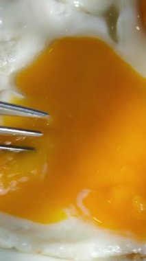 Bir yumurtayı çatalla cıvık bir yumurta sarısı ile kesmek imkansızdır. Bütün yumurtayı kaldırmak imkansızdır. Yumurtanın sarısı dışarı akar. Yüksek kalite 4k görüntü