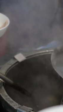Vietnam Phobo Çorbası. Açık büfedeki büyük kaplardan sıcak çorba servis eden eller. Taze ve ev yapımı mutfağı ön plana çıkarıyor. Yüksek kalite 4k görüntü