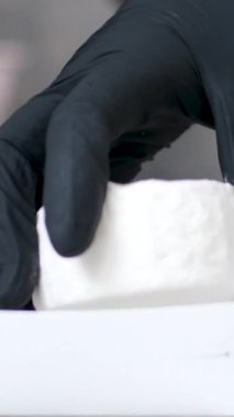 Siyah eldivenli eller, bir parça peyniri, içinde yiyecek olan bir kağıt kutuya katlıyor. Yüksek kalite 4k görüntü