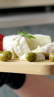 Domatesler vişne ve roka dönüşümlü. Tabakta zeytin peyniri ve domatesli Cherem ahşap tepside kadın elleri güzel sağlıklı yemekler sunuyor peynir tadında feta peyniri