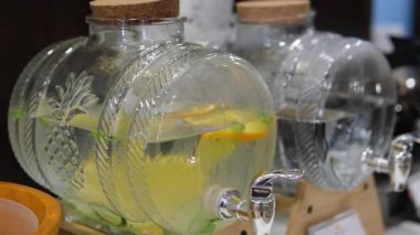 Cam içecek dağıtıcıları. Açık havada açık havada açık büfede açık büfede siyah rafta limonata ve portakal standı bulunan büyük kavanozlar dolusu soğuk limonata. İçkili masalar, el işi hediye kutuları.