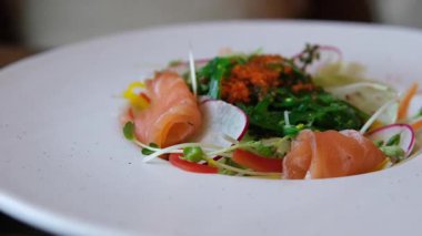 Ellerinde çatal bıçak takımı, somonla salata dilimleme, restoranda lezzetli bir öğle yemeği. Yüksek kalite 4k görüntü