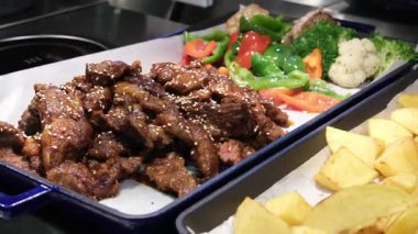 Izgara et sebzesi. Tepsilerde kızarmış et ve susamlı Asya mutfağı sebzeleri brokoli domates havuçları güzel sunum iyi yemek seçimi