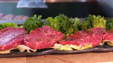 Biftek ve sosis pişirilmiş bir ızgaranın üstünde maşalı bir el bu yemek pişirme videosundaki ızgara yüzeyinden bir biftek alıyor. Yüksek kalite 4k görüntü