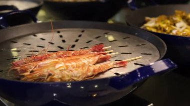 Şef karidesleri ızgarada pişirecek, her biri yemek pişirme yeteneğinin göstergesidir. Izgaranın sihrine şahit olun. Karidese dumanlı bir tat veriyor. Izgaranın kokusuna kapıl..