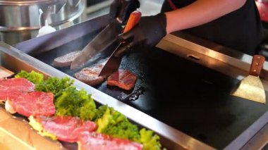 Izgarada çiğ biftek. Izgara et. Çiğ biftek ızgara için hazır. Et ızgarada pişiyor. Tanınmayan bir şef restoranda ızgarada biftek hazırlar..