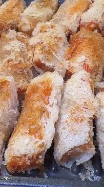 Yumurta ruloları kızgın yağ tenceresinde kızartılıyor ve metal bir kaşık ileri geri hareket ediyor. Yüksek kalite 4k görüntü