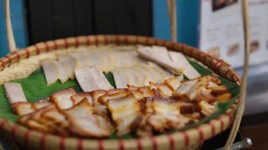 Geleneksel jambonu bir bıçakla tahta bir kesme tahtasının üzerinde parçalara ayırmak. İnce et dilimleri. Lezzetli yemek ve yemek kavramı. Sepet dilimlenmiş et