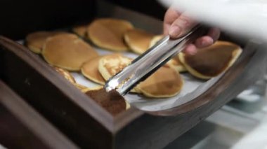 Bir kafede bir fırıncı krep yapıyor ve hazır krepleri tepsilere koyuyor. Sahne bir tatil köyünde bir yazlık kafe. Yüksek kalite 4k görüntü