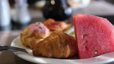 Beyaz tabak kruvasan çöreği ve karpuz kahvaltısı. Yüksek kalite 4k görüntü