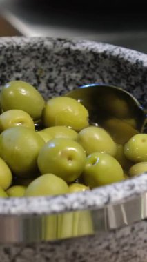Bir kase yeşil zeytinyağı, beyaz arka planda yeşil zeytinyağının üzerine nazikçe altın zeytin yağı dökülmüş. Akdeniz yemek sahnesi yatay formatta. Yüksek kalite 4k görüntü
