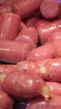 Mavi eldivenli eller çiğ sosisleri yarı yarıya kesiyor, yakın plan. Yüksek kalite 4k görüntü