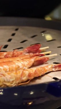 Şef karidesleri ızgarada pişirecek, her biri yemek pişirme yeteneğinin göstergesidir. Izgaranın sihrine şahit olun. Karidese dumanlı bir tat veriyor. Izgaranın kokusuna kapıl..