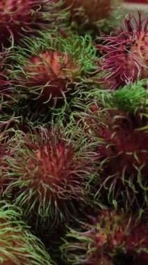 Yerel çiftçi pazarında sergilenen taze, sağlıklı, kırmızı Rambutan meyve yığınının yakın plan görüntüsü. Taze hasat edilmiş rambutan meyvesi görüntüsü.