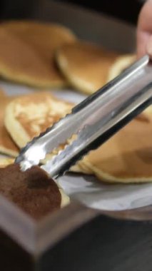 Bir kafede bir fırıncı krep yapıyor ve hazır krepleri tepsilere koyuyor. Sahne bir tatil köyünde bir yazlık kafe. Yüksek kalite 4k görüntü