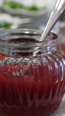 Ahududu reçeli, marmelat ya da taze böğürtlenli kavanozda konfeksiyon. Kırmızı reçeli kaşıkla alıyorum. Üst Manzara. Tatlı yemek. 4k video. Yüksek kalite 4k görüntü