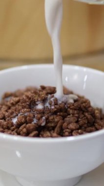 Çikolatalı kahvaltı gevreğiyle kaseye süt dökmek, yakın çekim. Yüksek kalite 4k görüntü