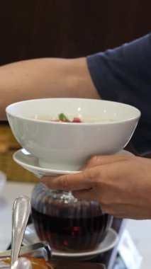 Açık büfedeki büyük tencerelerden sıcak çorba servis eden ellerin yakın çekimi, taze ve ev yapımı mutfağa vurgu yapıyor. Yüksek kalite 4k görüntü