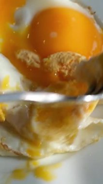 Yeşil tabakta kızarmış yumurta ve ekmek yemek. Yakın plan. Bakış açısı. Renkli arka plan. Tostlu geleneksel kahvaltı. Güneşli bir gün. Dikkatsizce lekelenmiş.