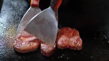 Biftek ve sosis pişirilmiş bir ızgaranın üstünde maşalı bir el bu yemek pişirme videosundaki ızgara yüzeyinden bir biftek alıyor. Yüksek kalite 4k görüntü