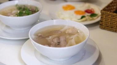 Taze yapılmış pho çorbası fasulye lahanası ve fesleğen yapraklarıyla süslenir. Kadın sıcak Asya çorbasının tadını arttıran malzemeler ekler. Geleneksel Vietnam çorbası, mis kokulu çorba ve taze bitkilerle birlikte..