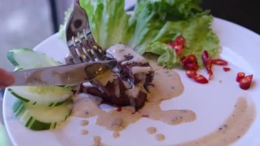 Biftek sosu. Kızarmış biftek, yeşillik, domates, salatalık dilimlerinden oluşan ılık salata. Yüksek kalite 4k görüntü