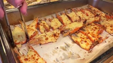 Biz usta bir şekilde ağız sulandırıcı karides ızgarası hazırlarken... -... üzerine yapışkan peynir sosu dökülmüş. Hareketli pazarlardan, cızırdayan ızgaralara, deniz ürünlerinin lezzetini tecrübe edin. 