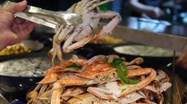 Geniş bir tavada servis edilen ve canlı kabuklarını ve leziz dokularını sergileyen yeni pişmiş kırmızı yengeç yakın çekimi. Mutfak ve deniz ürünleri teması için ideal. Yüksek kalite 4k görüntü