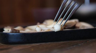 Ev aşçısı, istiridye mantarlarını parçalara ayırır. Ahşap masa, mutfak gereçleri, sebzeler, şifalı otlar ve yemek malzemeleri ile rahat bir mutfak. Sağlıklı vejetaryen yemekleri, aşçılık, yemek tarifleri, yemek blogları. Yüksek