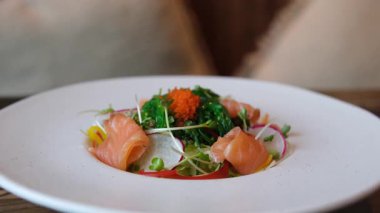 Ellerinde çatal bıçak takımı, somonla salata dilimleme, restoranda lezzetli bir öğle yemeği. Yüksek kalite 4k görüntü