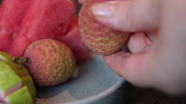 Genç bir kız bir liçi meyvesini soymaya çalışır. Taze liçi yiyen kız. Bir kadın ve liçi meyvesi. Meyve yeme kavramları. Yakın çekim 4K videosu. - Evet. Yüksek kalite 4k görüntü