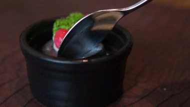 Tabağa kahve jölesi koyarken çekilmiş bir video. Yakın plan. Sağdan sola. Güzel bir tatlıyı kaşıkla kepçelemek zordur, esnetir, her şey paramparça olur., 