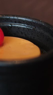 Bir el, beyaz bir tabağı dolduran karamelize edilmiş büyük bir pudingin üstüne kiraz koyar. 4K ağır çekim. Yüksek kalite 4k görüntü