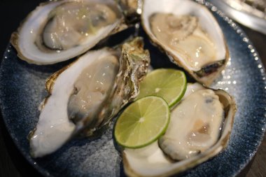 Buzlu, limonlu, limonlu ve beyaz şaraplı istiridyeler siyah bir arkaplanda yatıyordu. Yüksek kalite fotoğraf