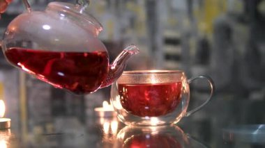 Mutfaktaki ahşap masada sıcak çayla duran kupa. Küçük bir kaşıkla bir el şeffaf bir fincanda çay karıştırır. Çay poşetiyle kaşığı yavaş çekimde karıştırmak. - Evet. Yüksek kalite 4k görüntü