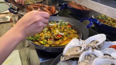 Cruiser 'da büyük bir balık yemeğinin servis edildiği açık büfe sahnesi. Balık, aşındırıcı bir tabağa konmuş sebze ve sosla süslenir. Birisi balıklara maşa veriyor. 