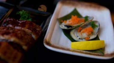 Limon dilimleri ve garnitürlü taze istiridye yakın çekim, gurme deniz ürünleri aperatifi. Taze deniz ürünleri ve gurme yemeği. Yüksek kalite 4k görüntü