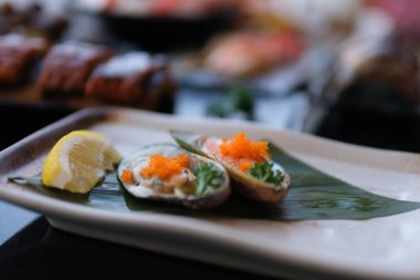 Buzlu taze istiridye ve yeşil otlarla süslenmiş yuvarlak tabakta kızarmış soğan, deniz ürünleri sosu ve biber ezmesi. Yüksek kalite fotoğraf