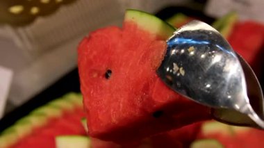 Karpuz kesiyorum. Kesme tahtasındaki karpuz dilimleri. Meyvenin kırmızı posası. Güneşli bir günde masada yemek. Yüksek kalite