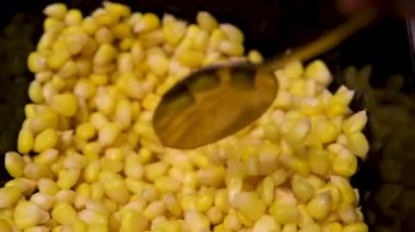 Tabakta lezzetli mısır yiyen bir kadın, evde çatalla yemek, yakın plan. Pişirme yemeği hazırlayın. Mutfak mutfağı, ev yemeği tarifi, sebzeler. Tatlı pişmiş.