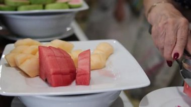 Karpuz kesiyorum. Kesme tahtasındaki karpuz dilimleri. Meyvenin kırmızı posası. Güneşli bir günde masada yemek. Yüksek kalite 4k görüntü. 